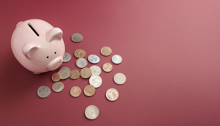 Pink piggy bank and scattered coins on a maroon background.